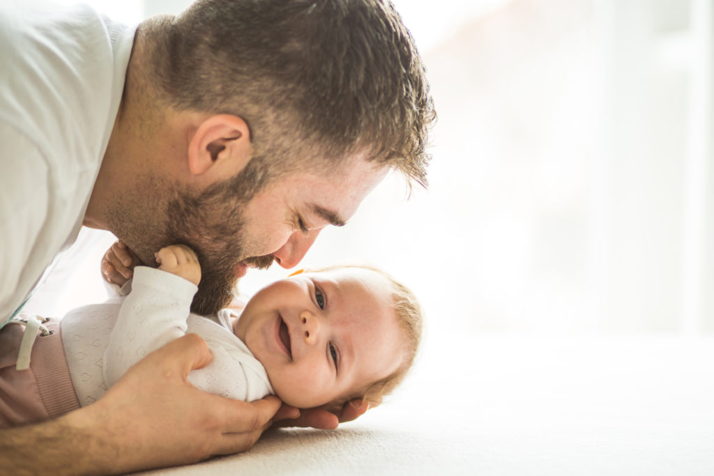 Happy mature father playing with his baby daughter (3 months old).